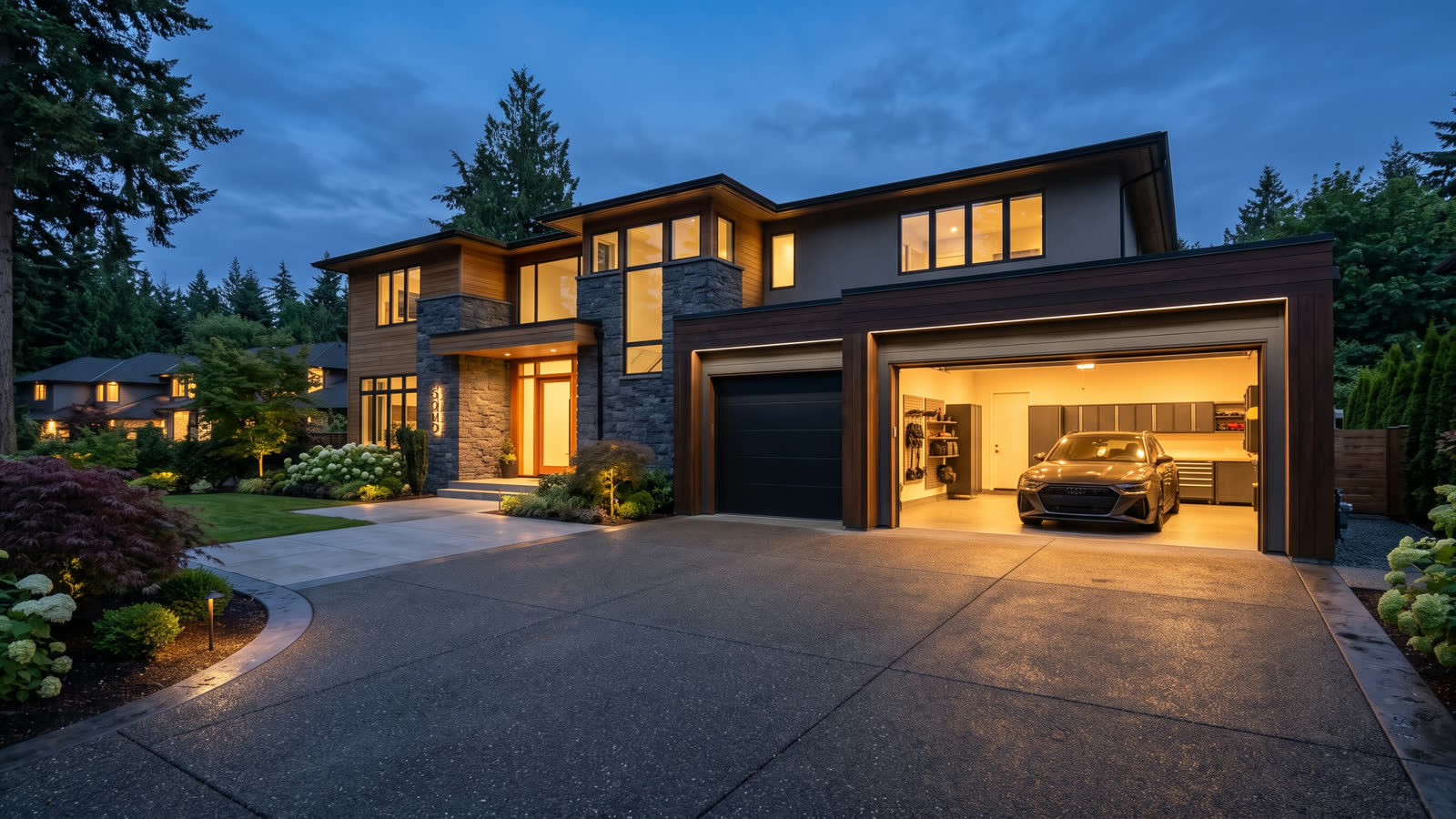 A modern black steel garage door on a suburban home at dusk, one bay open and lit