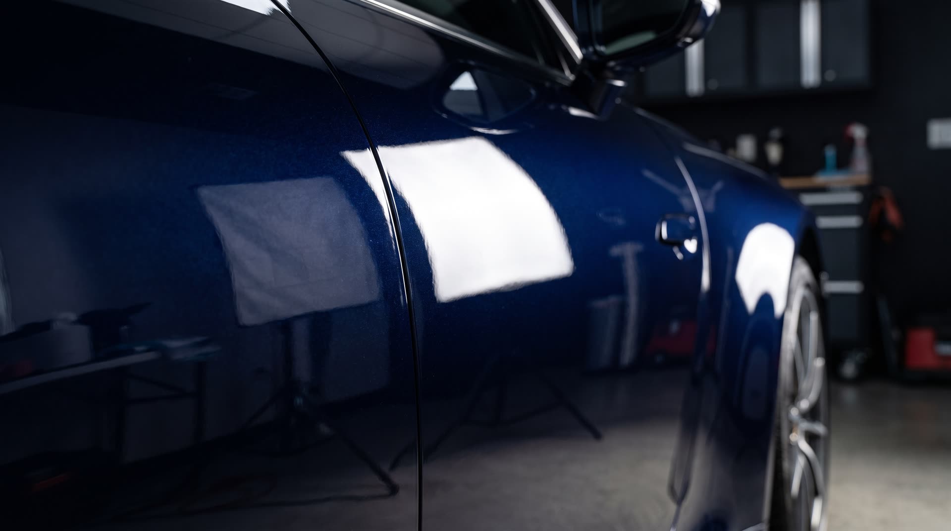 A freshly ceramic-coated dark navy panel under a raking light in the Lustre detailing bay